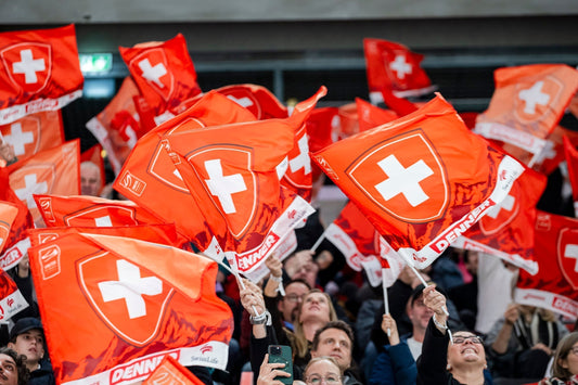 Crowd of fans waving Swiss flags in a stadium, supporting the Swiss National Ice Hockey Team