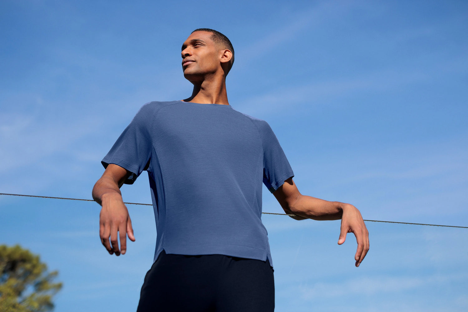 Man wearing a blue sleep t-shirt against a clear blue sky
