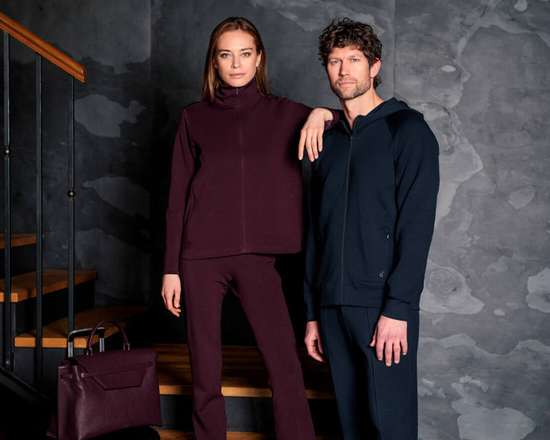 Two people standing on a staircase wearing matching outfits against a dark wall.