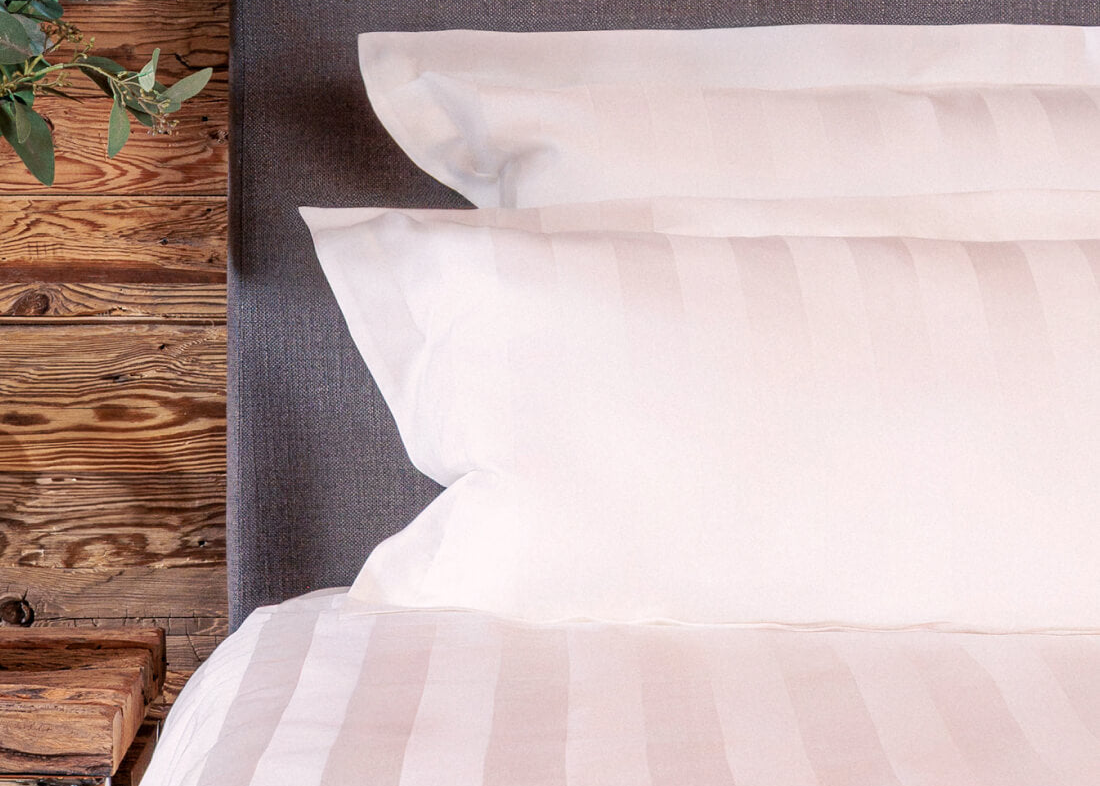White pillows on a bed with a wooden headboard and plant.